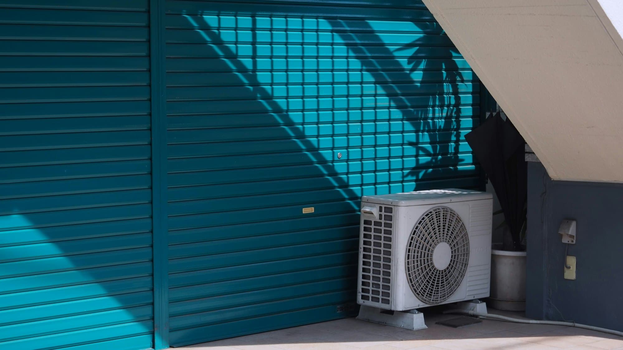 Unité extérieure de climatisation posée au pied d'une façade